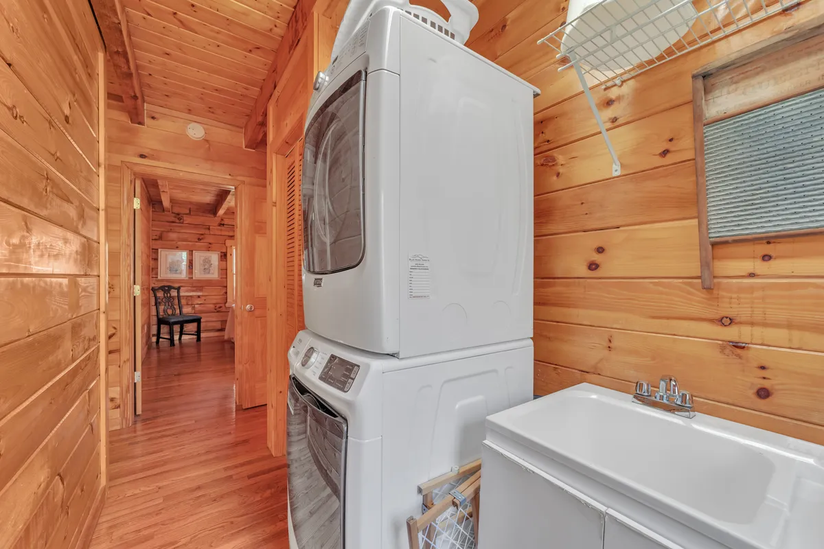 A practical mudroom area with stacked washer and dryer, a laundry sink, and warm wooden paneling. The space is neat and functional, emphasizing cleanliness and tidiness for guests returning from outdoor or pet-friendly excursions.